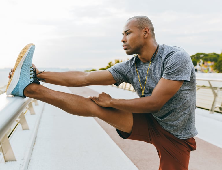 a man in a gray shirt is stretching his legs