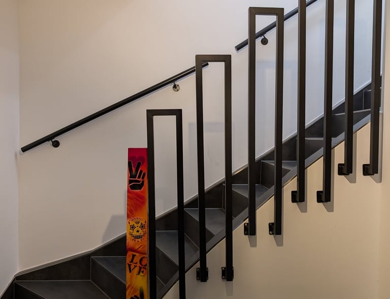 eine frisch sanierte Treppe, gefliest mit schwarzen Fliesen. im vordergrund ein  Treppengitter,