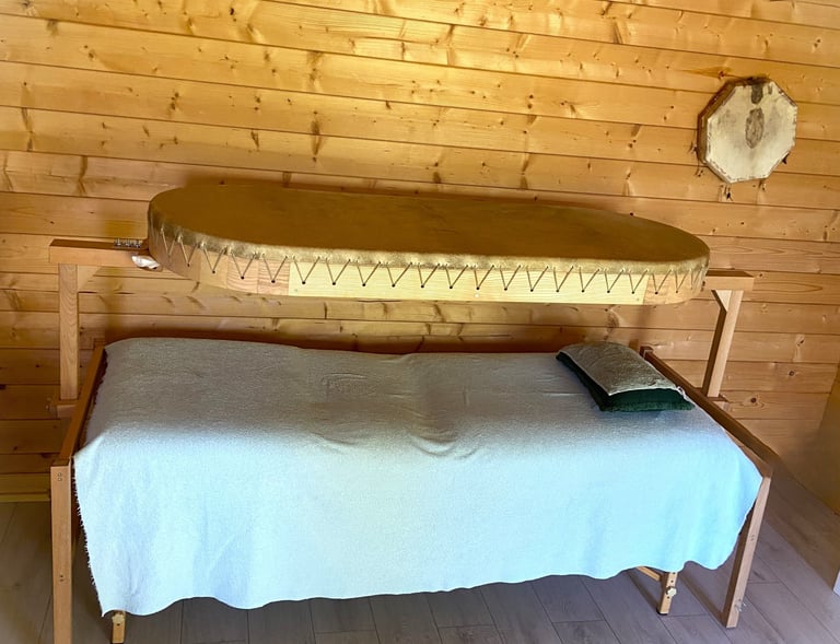une table de soin au dessus un grand tambour chamanique . la personne s'allonge et ressent la vibrat