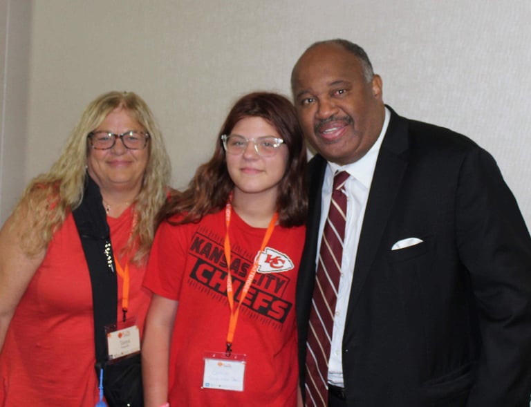 Dominic Carter at the Missouri Kinship Conference speaking with a teenager and her aunt who is raising her — highlighting fam