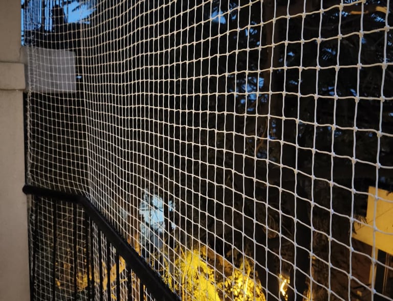 Installation team carefully fitting pigeon-proof safety nets on a high-rise balcony in Bangalore.