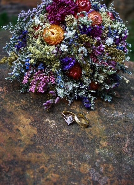 two rings and a bouquet of flowers on a stone