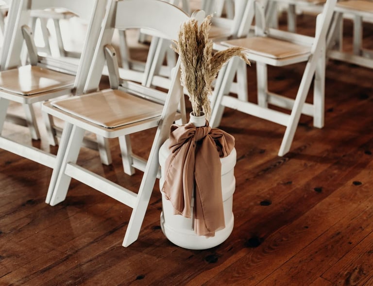 a vase of flowers in it next to rows of wooden chairs