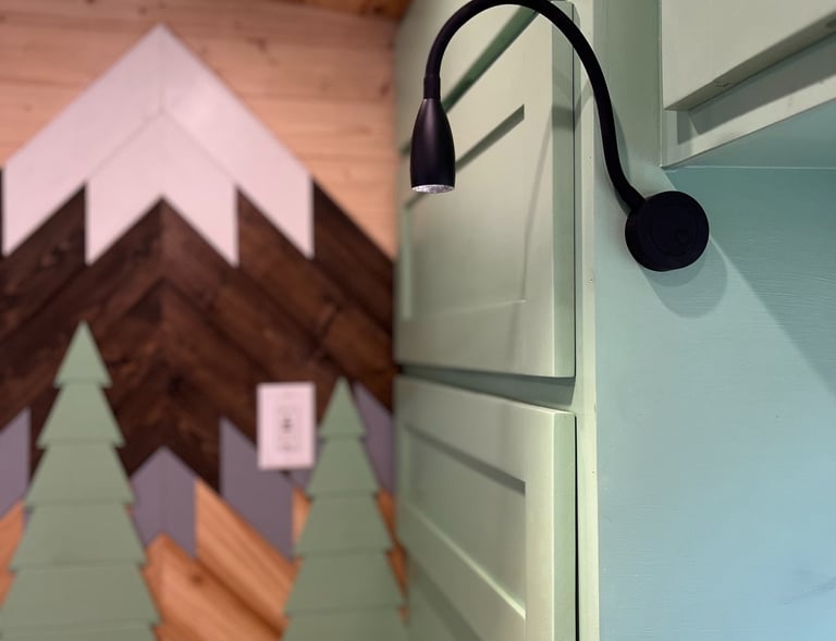 custom cabinetry inside schoolie bus featuring handmade mountain background for headboard of bed