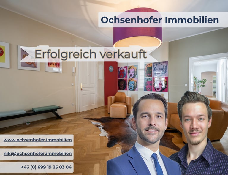 Real estate agents from Ochsenhofer Immobilien in front of a modern living room successfully sold.