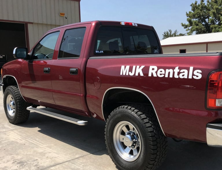 A team member from MJK Rentals securing a dumpster on the back of a flatbed truck, ready for transport.