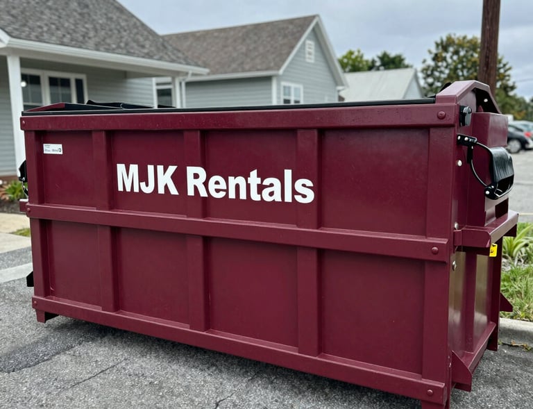 A large green dumpster filled with construction debris parked at a busy Manahawkin job site under a clear blue sky.