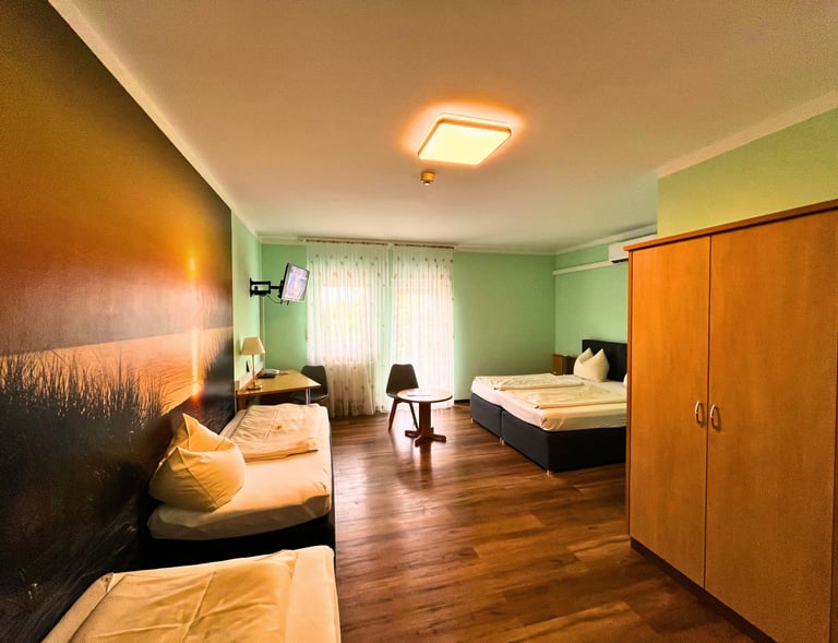 Modern hotel room with twin beds, sunset wall mural, wooden floors, and a spacious wardrobe.