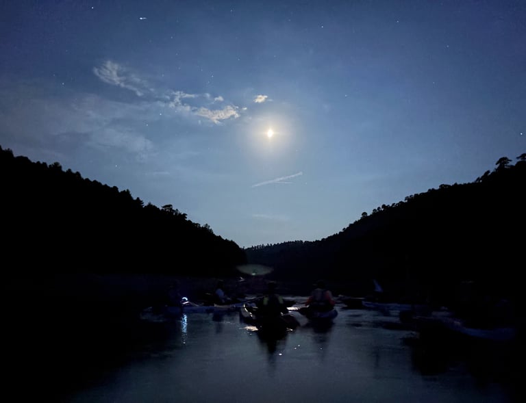 conjunto de piraguas a la luz de la luna en mitad del embalse de la Toba con montañas a contraluz