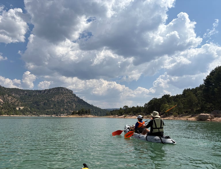 Piragua remando en el embalse de la Toba con un cielo nuboso precioso y montañas y vegetacion al fon