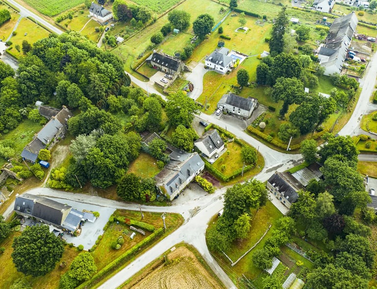 Vue aérienne d'un village rural Français avec des maisons en pierre, des jardins verdoyants et des r