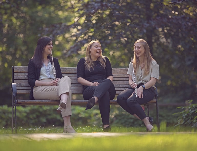 three women sitting on a bench in a park