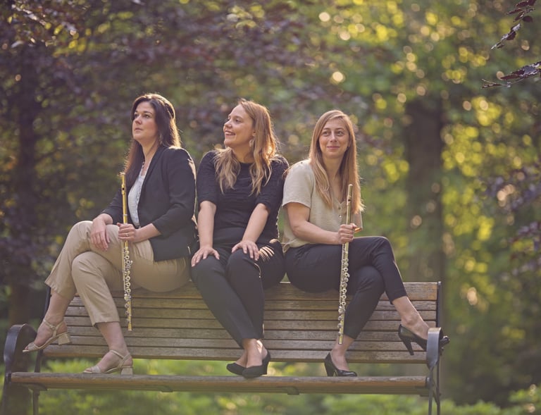 three women sitting on a bench in a park