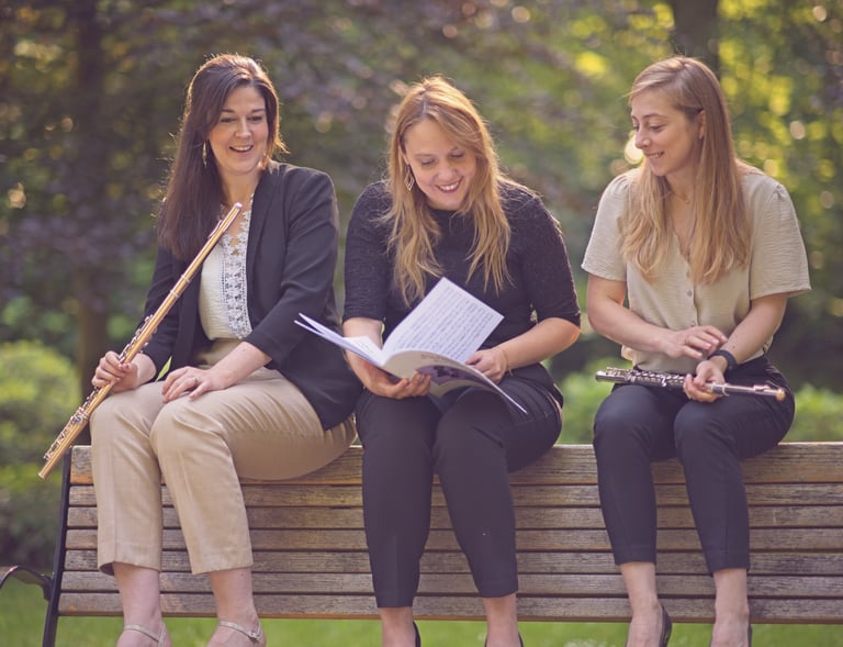 three women sitting on a bench in a park