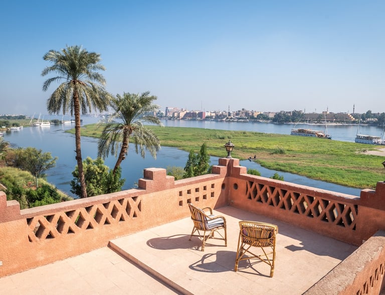 A scenic rooftop terrace overlooking the Nile River in Egypt with palm trees and cruise boats.