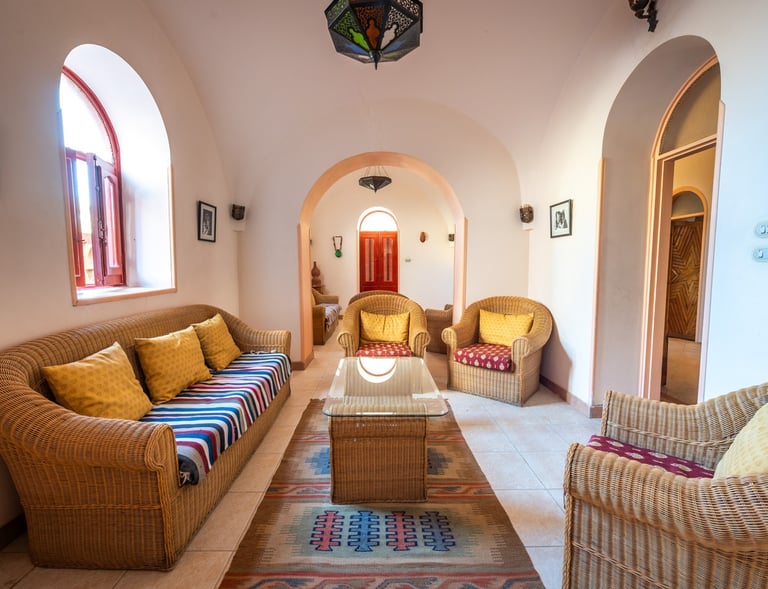 Traditional Middle Eastern living room featuring wicker furniture, colorful pillows, and arched doorways.