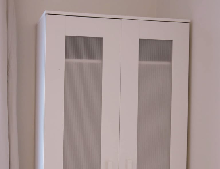 Built-in wardrobe in adult family home bedroom with shelves and hanging space for resident clothing.