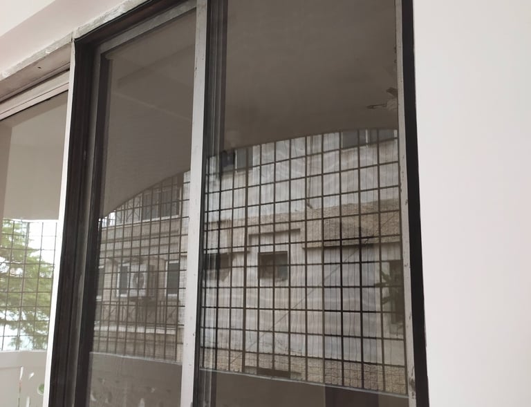 Installation process of a mosquito net on a window, showing the careful measurements and fitting.