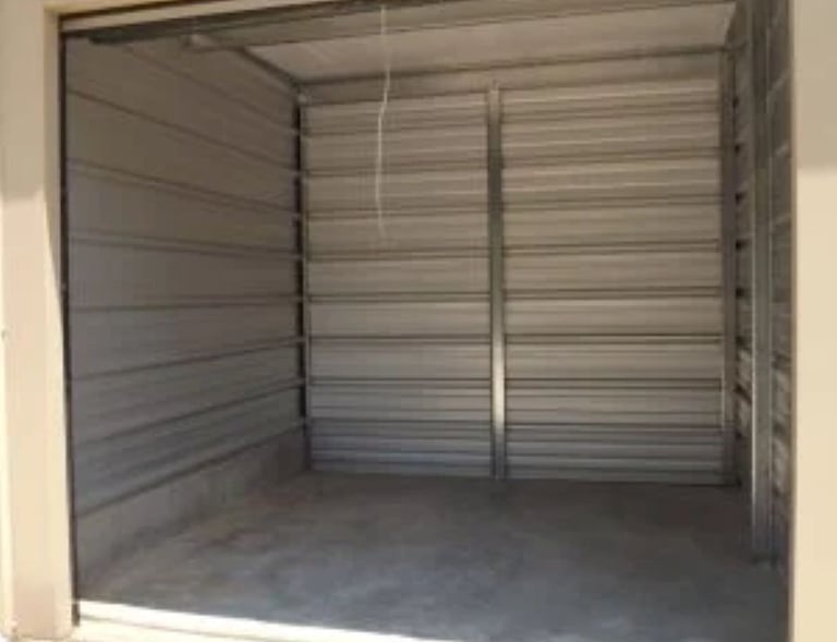 An empty 10X10 foot drive up self-storage unit with metal corrugated walls and a concrete floor.