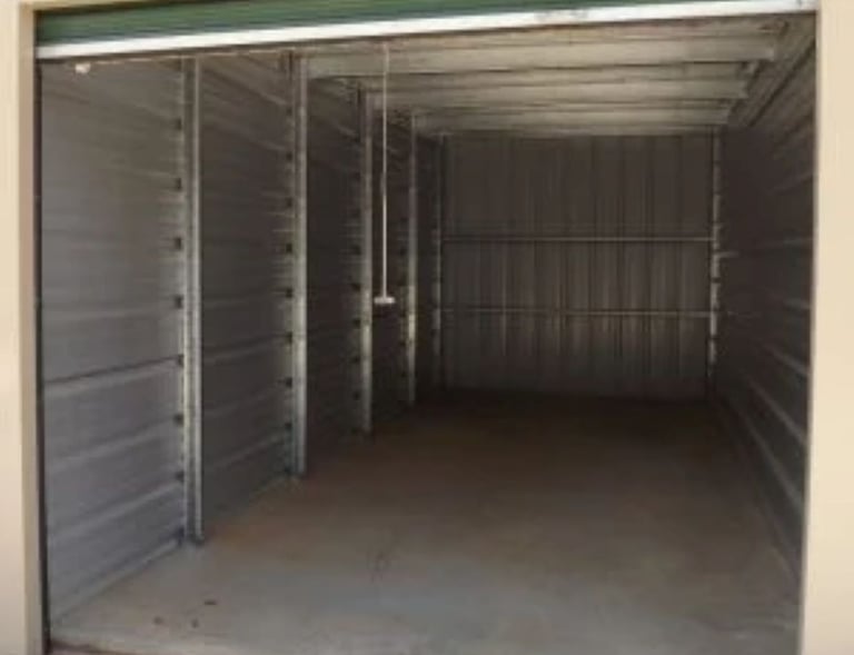10X25 foot empty metal self-storage unit with an open roll-up door and concrete flooring.