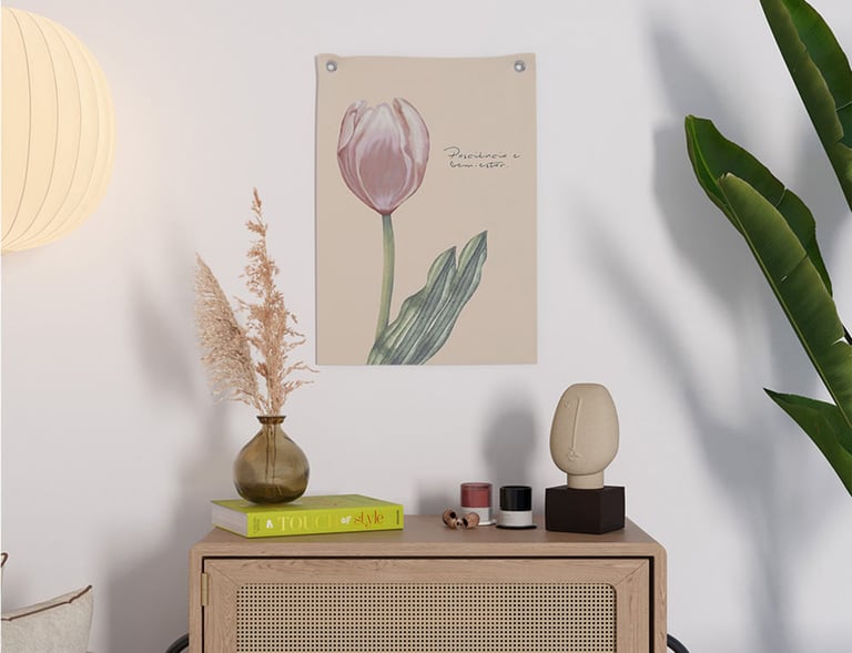 Decoração minimalista para casa com uma gravura de tulipa rosa na parede acima de um armário de vime