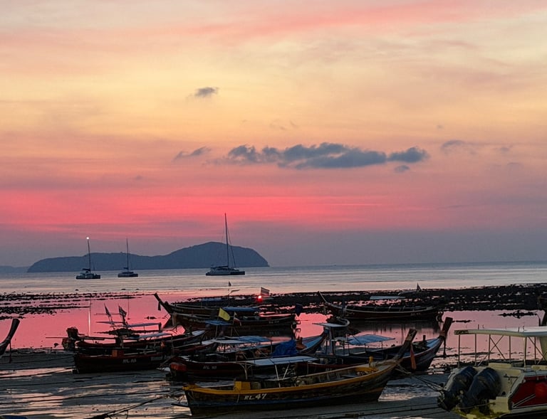 Sunset view over Rawai Beach with traditional Thai longtail boats near Yanui Apartments