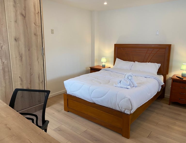 Habitación matrimonial amplia con cama cómoda, iluminación cálida y escritorio en hotel en Huayllay 