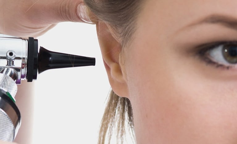 A doctor Porro performing an ear examination on a patient using a professional medical otoscope.