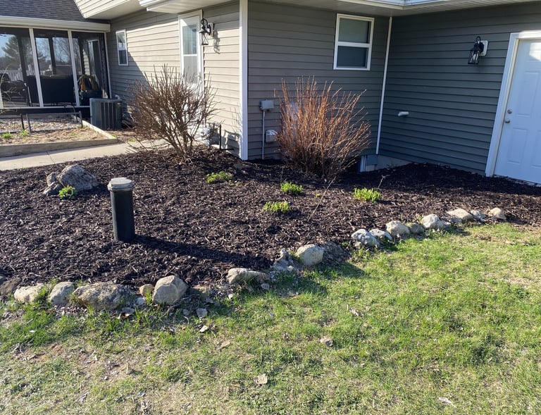 Professional residential landscaping with fresh mulch, trimmed shrubs, and natural stone edging