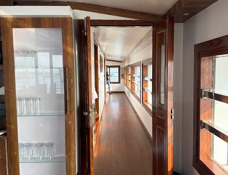 A luxury Alleppey houseboat featuring a furnished  deck, floating on a narrow canal r