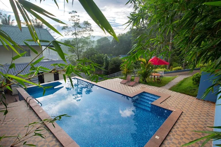 A infinity pool overlooking the rolling green tea plantations at a  Deluxe Hotel in Kerala