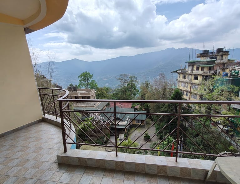 A cozy hotel room in Gangtok with a private balcony that opens up to a  a panoramic view 