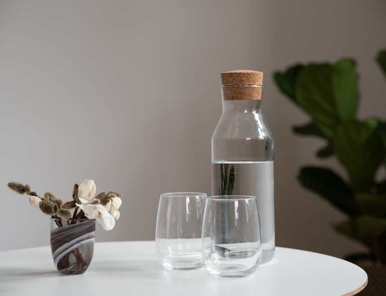 En kande med vand på et blomsterdækket bord