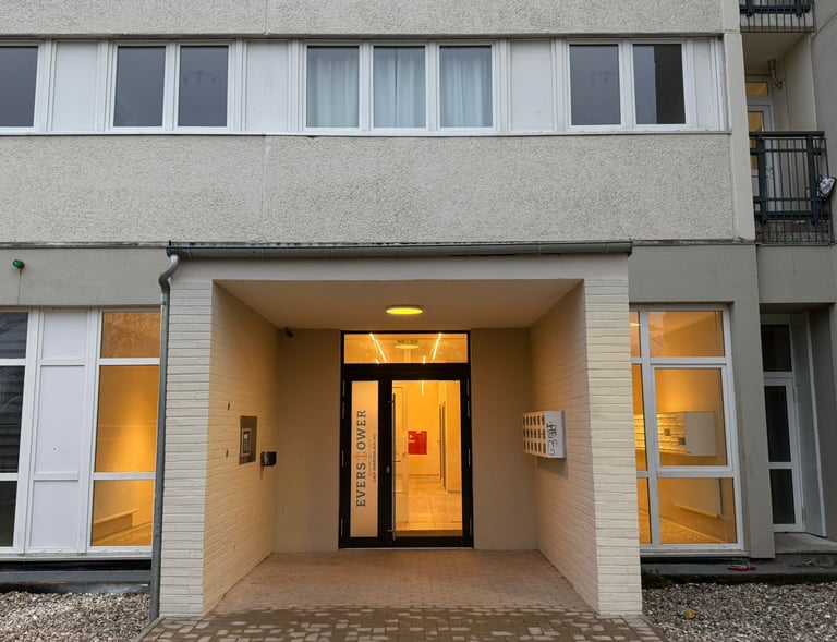 Modernisierter Eingangsbereich eines Wohngebäudes mit Glasfront und Leuchtbeschriftung