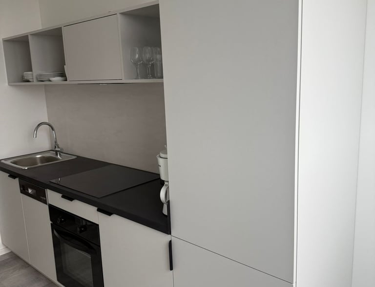 Moderne, minimalistische Einbauküche mit hellen Fronten und schwarzer Arbeitsplatte