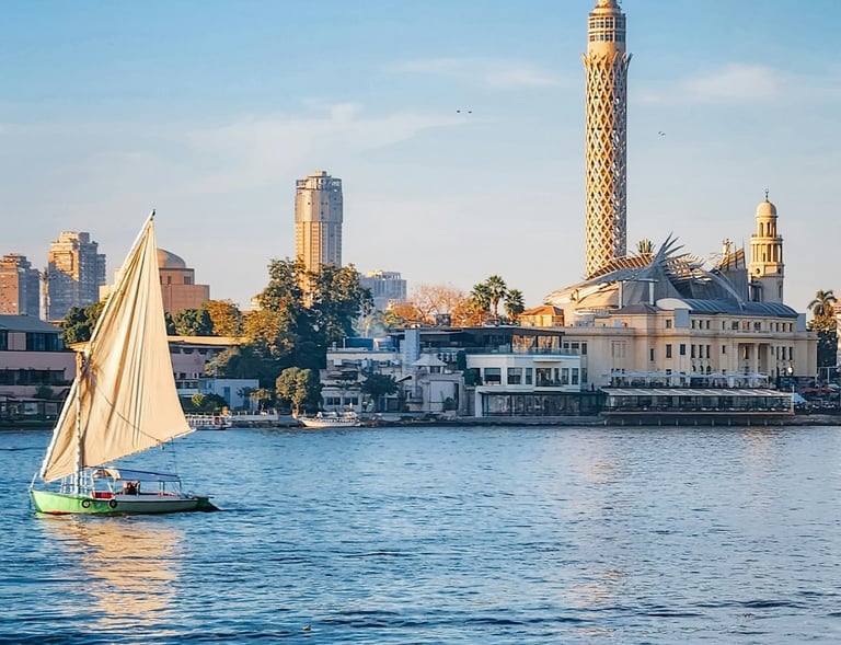 Traditional felucca sailboat on the Nile River with Cairo Tower in the background.