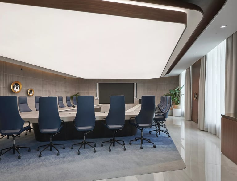 Modern corporate boardroom with a large conference table, blue ergonomic chairs, and professional office lighting.