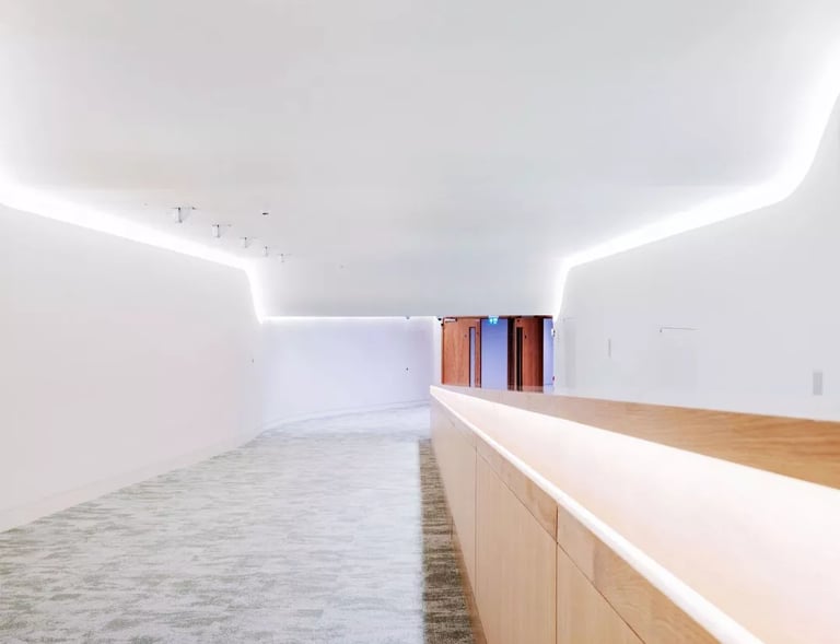 Modern minimalist white hallway with LED cove lighting and wooden wall paneling.
