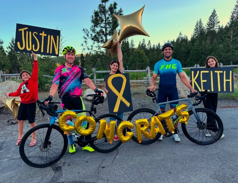 A group of people with balloons and a congrats sign with two cyclists