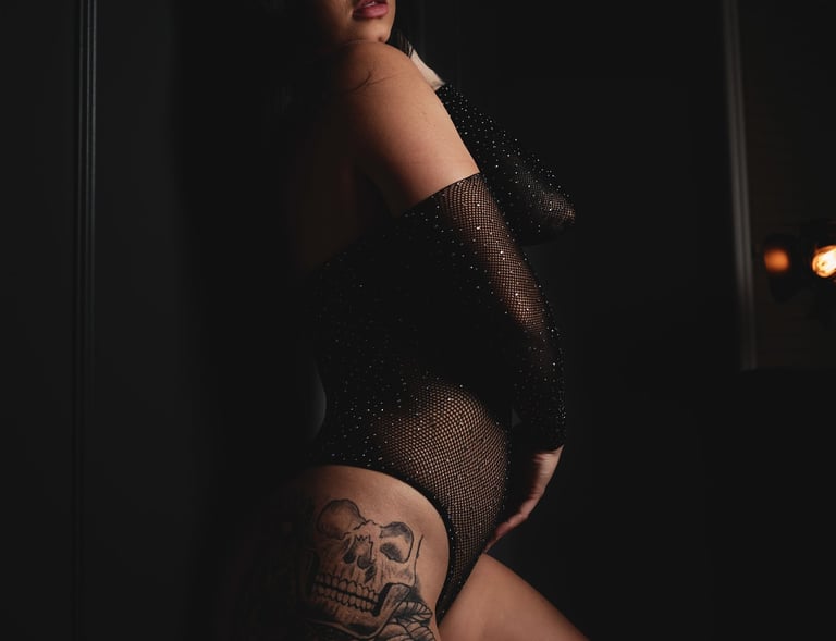 a woman in a black bodysuit and stockings with tattoos on her butt