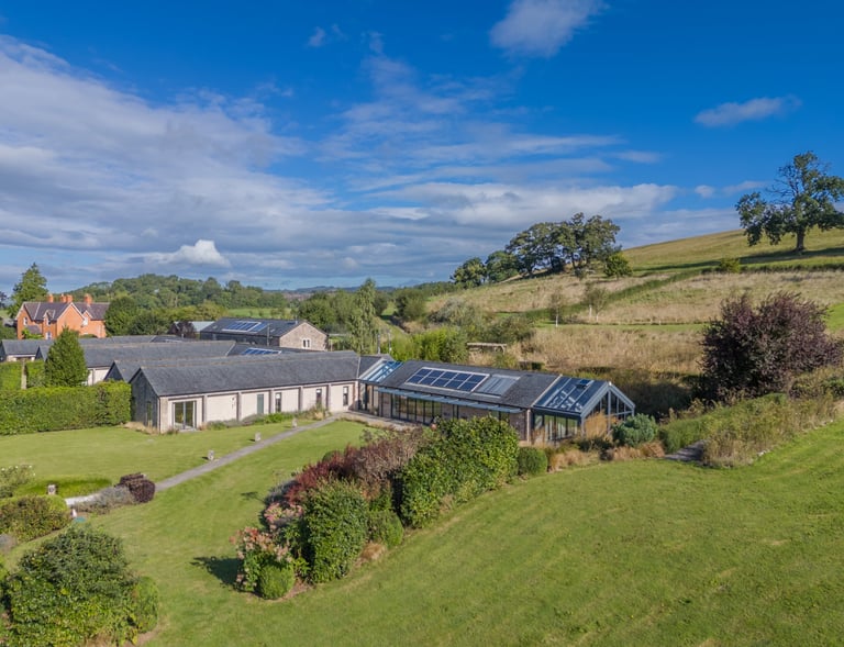 a stunning barn conversion with a large lawn and solar panels