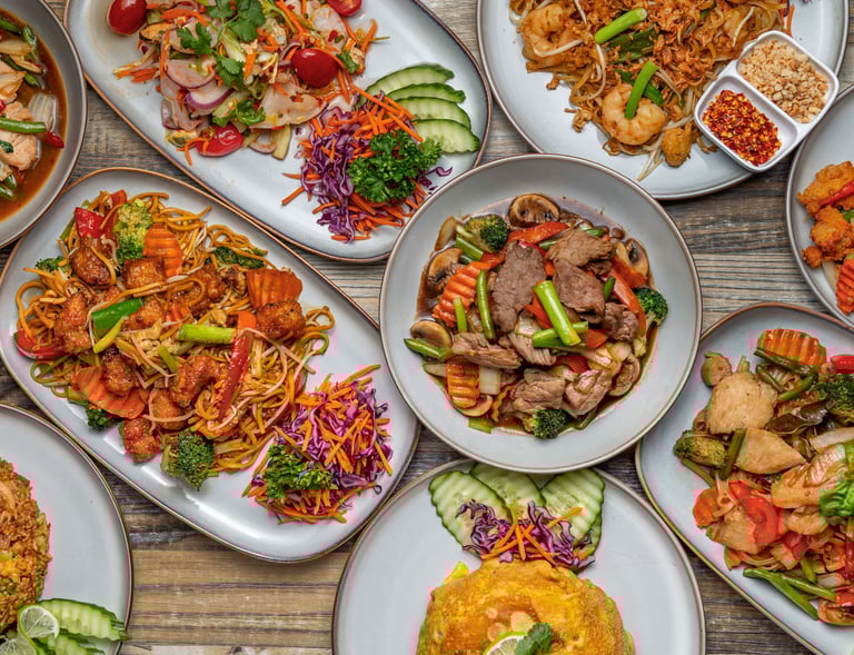 Overhead view of a large assortment of authentic Thai dishes, including beef and vegetable stir-fry