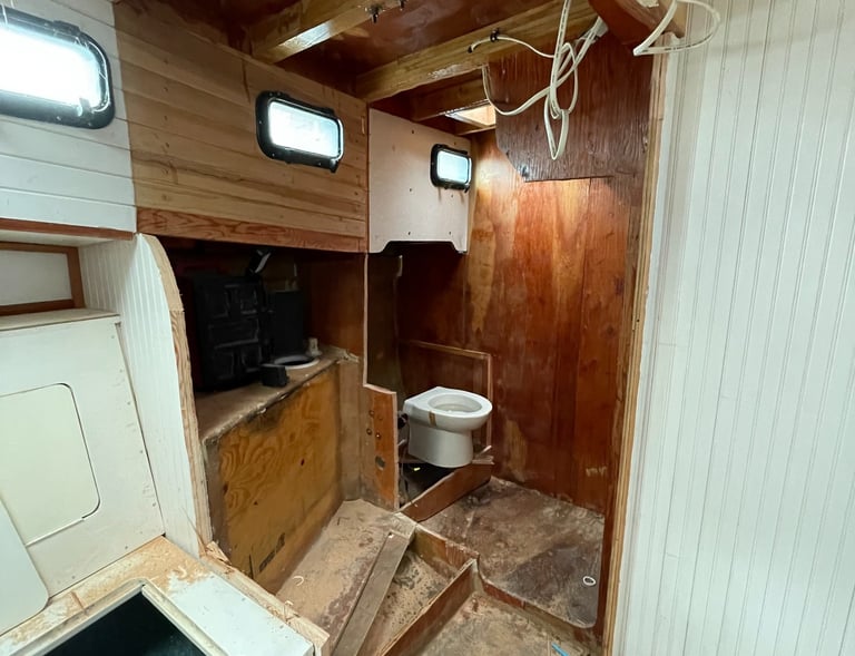 walls to the head (bathroom) cut open with a toilet perched in an unfinished wooden room