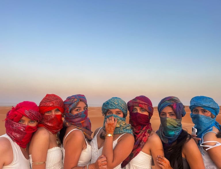 Mulheres brasileiras montado em camelos nas dunas do Deserto do Saara, pôr do sol.