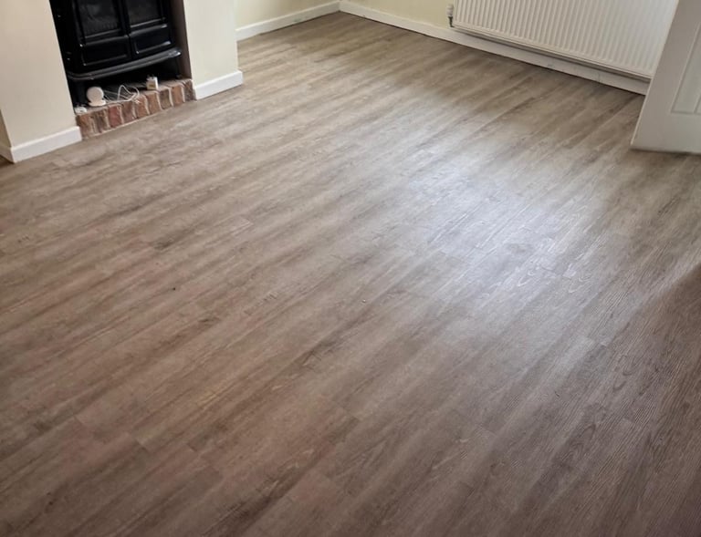 Modern living room featuring light oak wood-effect laminate flooring and a black fireplace stove.