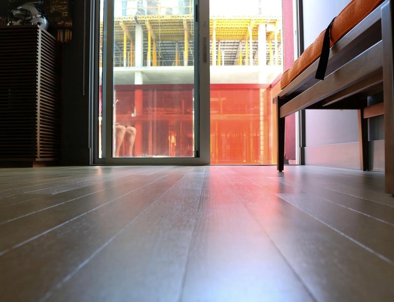 Low-angle view of polished hardwood floors leading to a sliding glass door with city views.