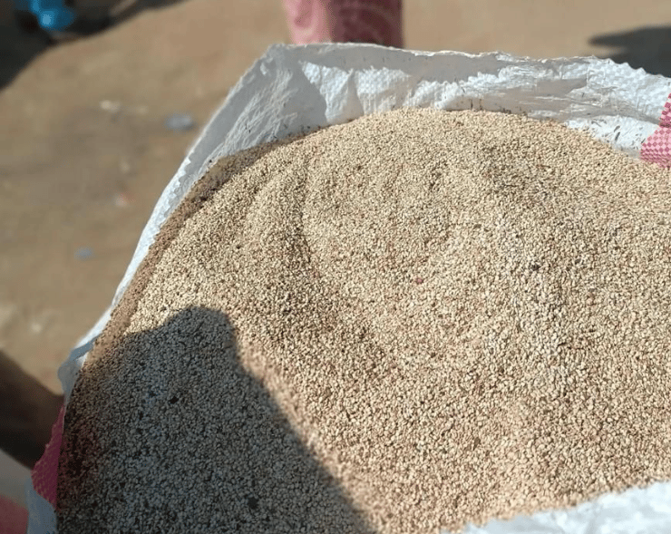 A large white sack filled with organic sesame seeds at an outdoor agricultural market.