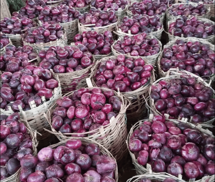 Woven baskets filled with fresh red onions at a vibrant local produce market.