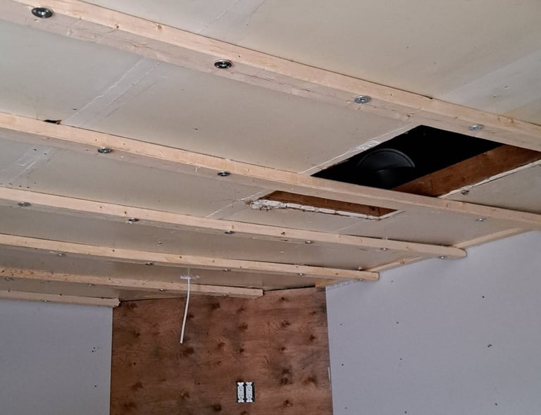 Ceiling strapping and drywall installation above fireplace during residential interior renovation