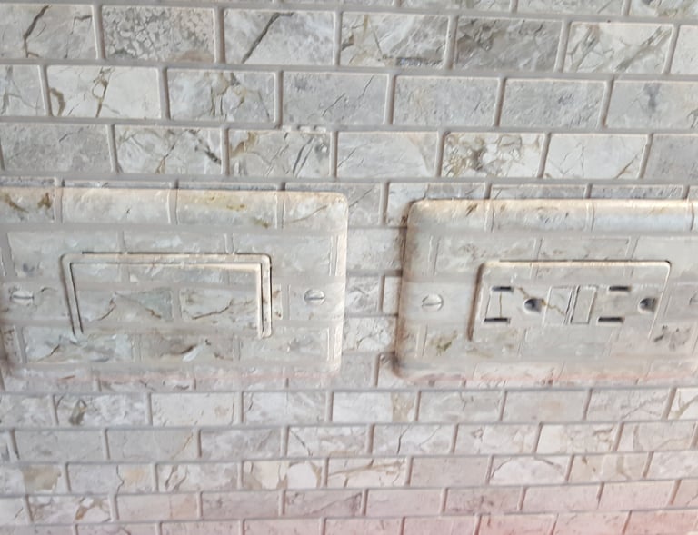 Switch plate faux finished to match the marbled tiles of this backsplash to hide them nicely.